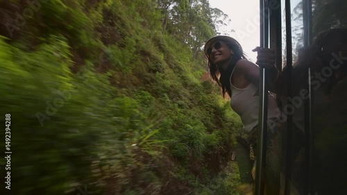 Happy passenger woman tourist stand by doorstep enjoy popular train ride journey Kandy to Ella and admire Sri lanka lush jungle landscapes. Embrace freedom, curiosity, wonder and serenity concept