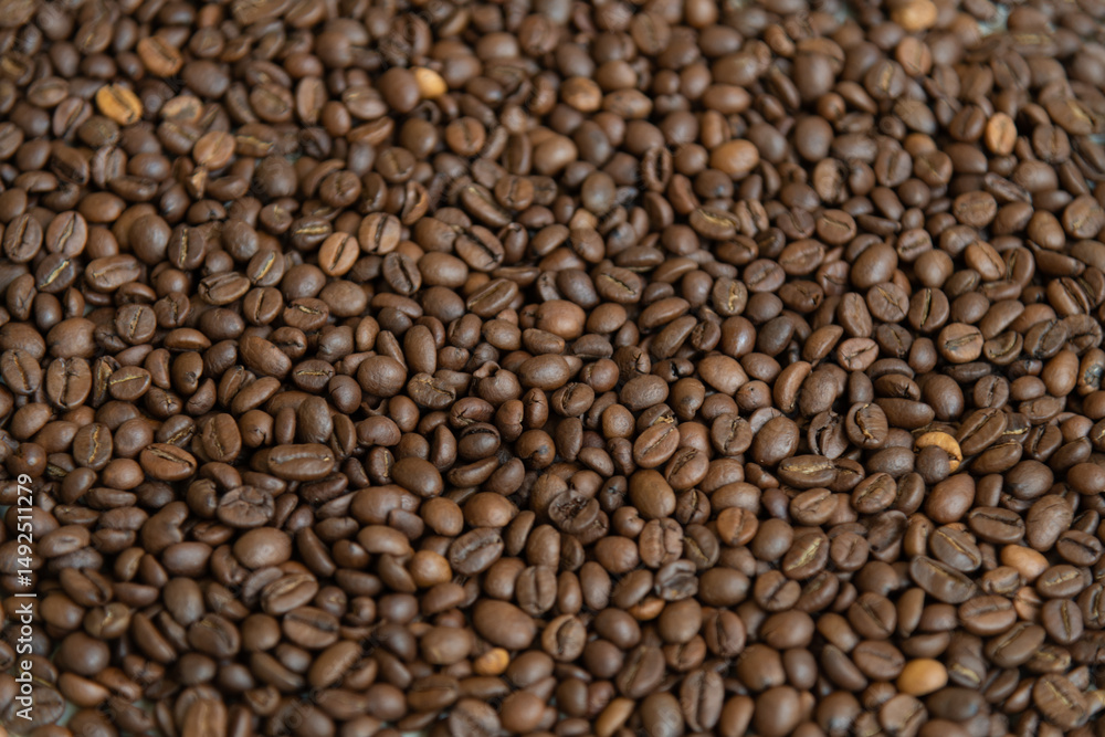 Dark roasted coffee beans are spread out on surface, showcasing their rich brown color and textured background. This display highlights the quality and variety of arabica or robusta beans. Copy space. Dark roasted coffee beans are spread out on surface, showcasing their rich brown color and textured background. This display highlights the quality and variety of arabica or robusta beans. Copy space.