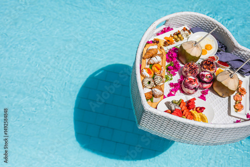 Floating breakfast served in luxury resort pool with fresh fruits, juice, healthy breakfast and fruit plate by resort pool. Exotic summer diet. Tropical beach lifestyle. Abstract travel vacation scene