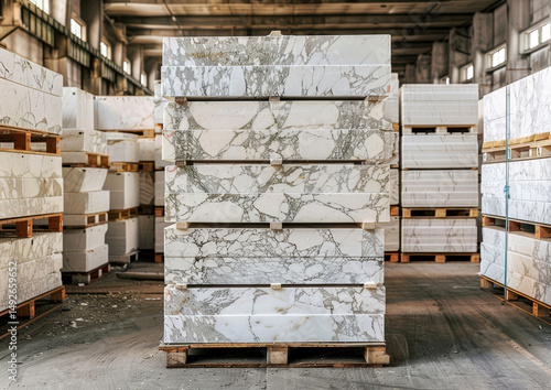 White marble slabs are neatly stacked on pallets inside a spacious warehouse, prepared for upcoming projects and installations
