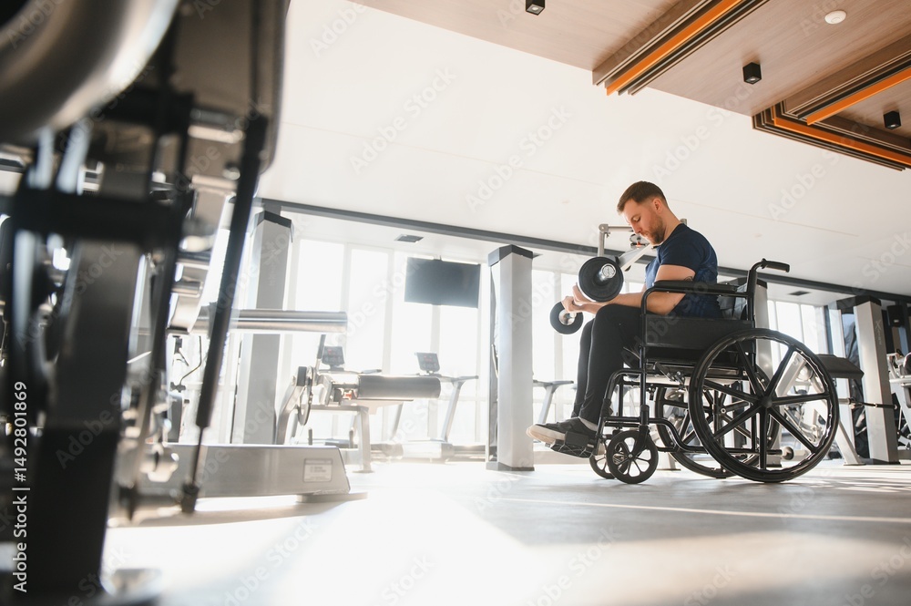 Man in wheelchair lifting weights during rehabilitation in gym Man in wheelchair lifting weights during rehabilitation in gym