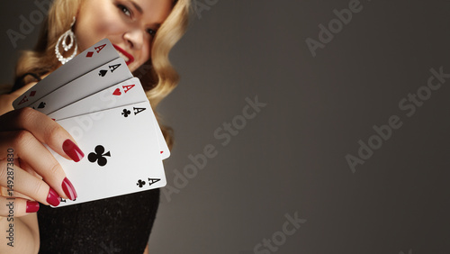 Four aces playing cards in woman's hand. Player with poker quads combination. Elegant female hands with red manicure