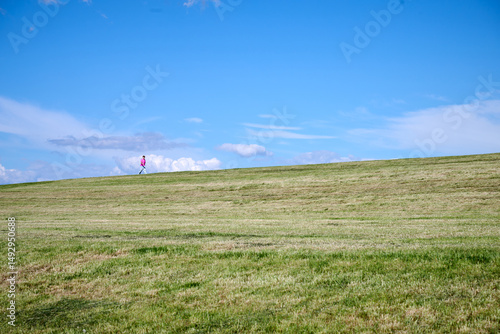 Lone Walker on a Grassy Hill