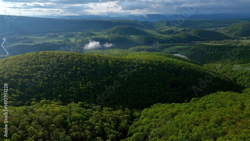 Rolling green hills and mountains under blue sky with clouds in early morning sunlight in West Virginia Mountains