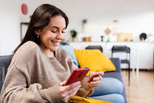 Wallpaper Mural Young happy woman making online payment using mobile phone and credit card, enjoying convenient and secure e-commerce experience from home Torontodigital.ca