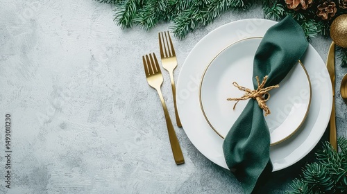 Stylish holiday dinner setting with white plates, golden flatware, and lush green napkins on a cool concrete table.