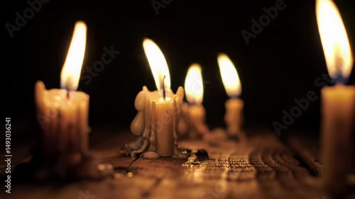 Several drippy old candles burning on a dark wooden surface with a black background, close-up view candlelight creating a warm and mystical atmosphere, footage