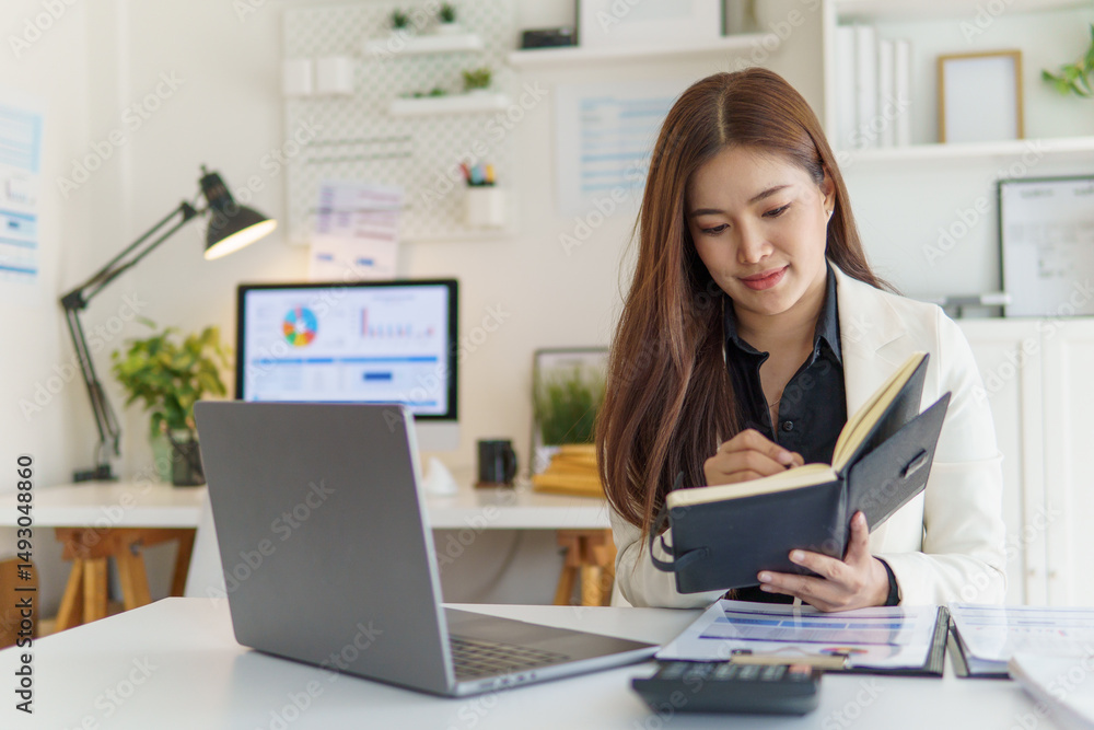 Businesswoman in white blazer taking notes and managing her workflow in a bright office. Businesswoman in white blazer taking notes and managing her workflow in a bright office.