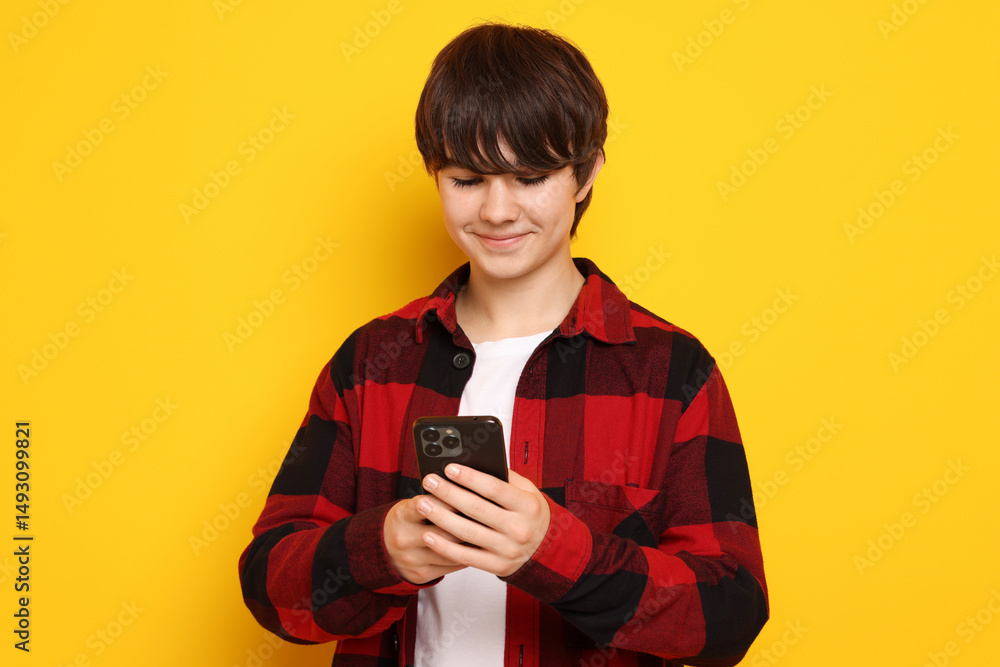 Teenage boy with smartphone on orange background Teenage boy with smartphone on orange background