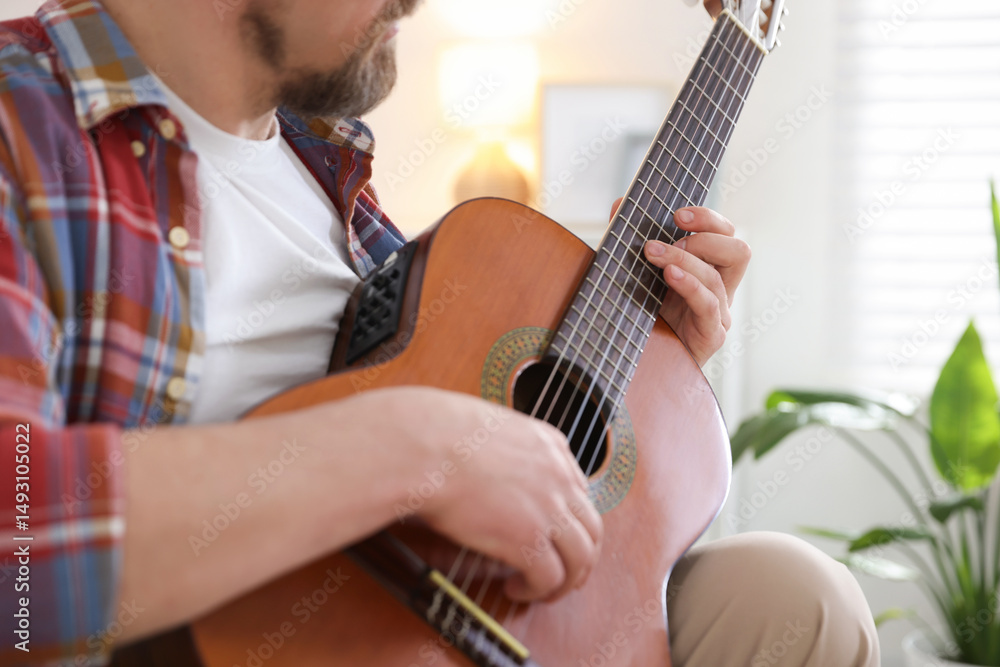 Fototapeta premium Man playing acoustic guitar at home, closeup