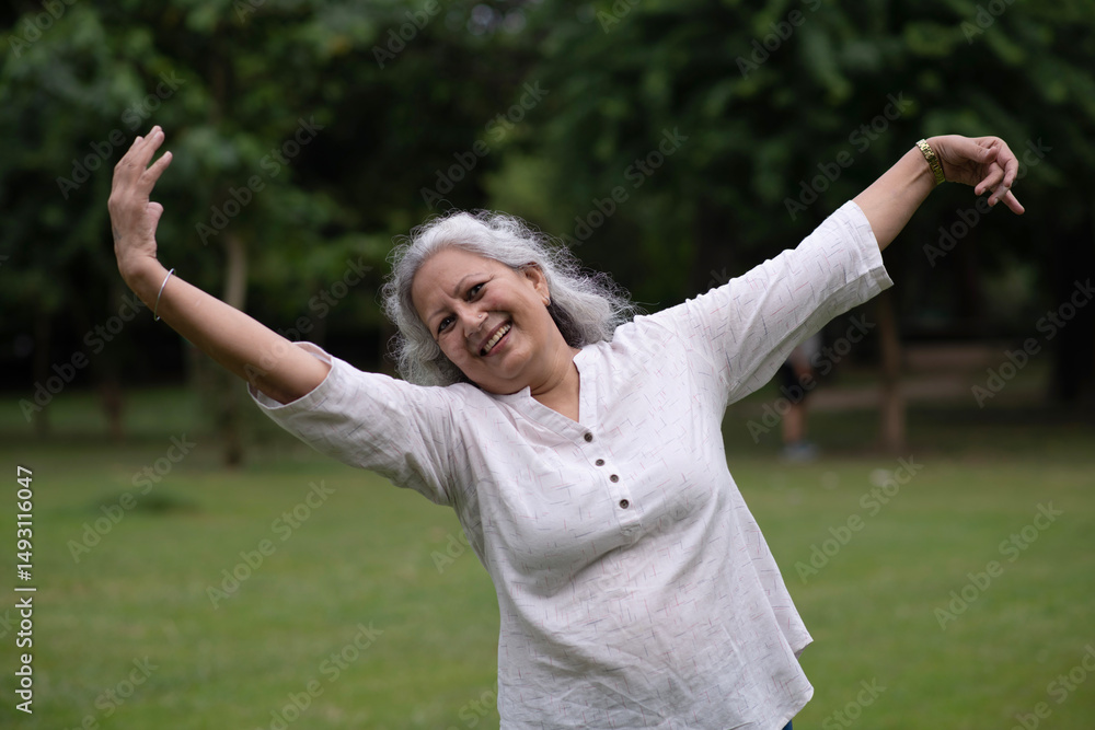 Indian happy senior woman spread her arms in environment nature like the wings of a bird. Happiness. Freedom. Elderly woman stands with one hand open in a park. Indian active old age at woman in park Indian happy senior woman spread her arms in environment nature like the wings of a bird. Happiness. Freedom. Elderly woman stands with one hand open in a park. Indian active old age at woman in park