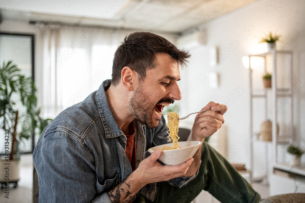 Hungry man greedily eating instant noodles at home Hungry man greedily eating instant noodles at home