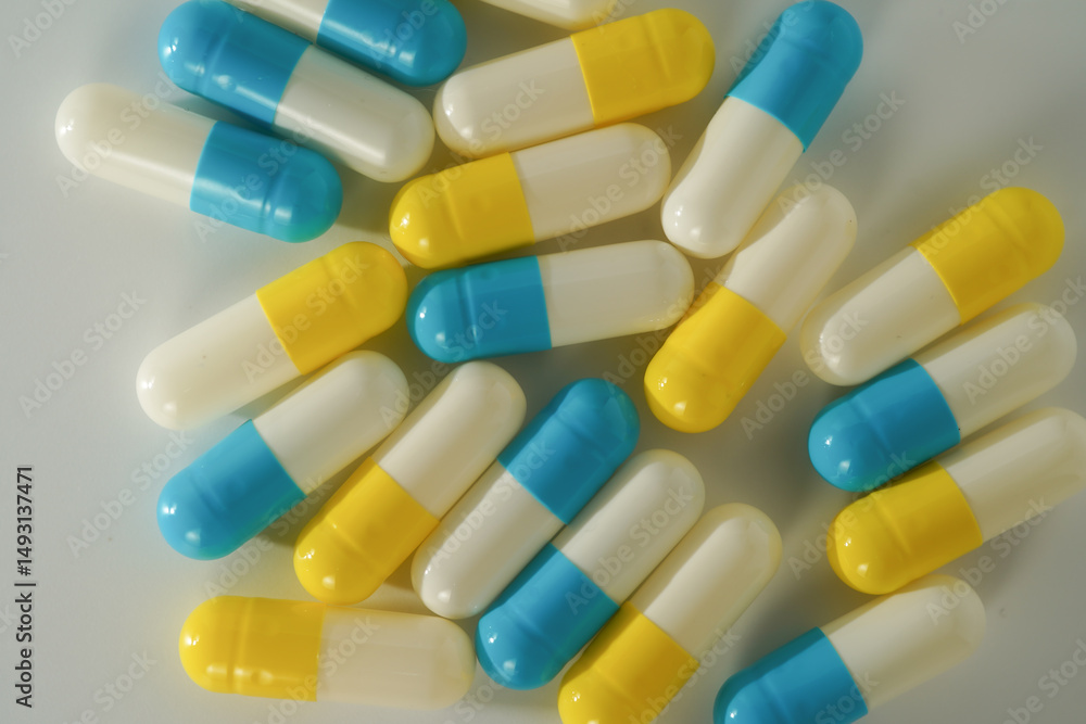 Capsules pill white blue yellow scattered on white surface, health care, medical background Capsules pill white blue yellow scattered on white surface, health care, medical background