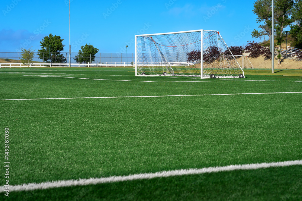 Fototapeta premium Soccer field with rollaway goal post on artificial synthetic green grass turf