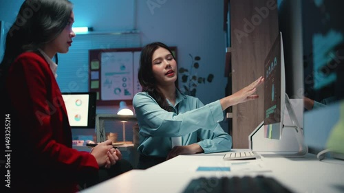Two tech professionals collaborate on a digital project, brainstorming and discussing ideas in an office setup during the night