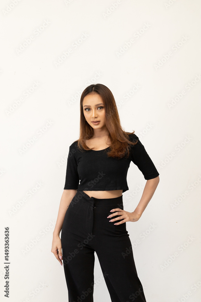 Attractive woman in a black crop top and trousers posing on a white background Attractive woman in a black crop top and trousers posing on a white background