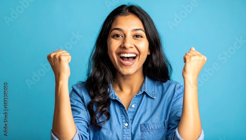 Portrait photo of a woman with a celebratory gesture with plain blue background