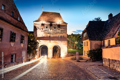 Illuminated evening view of Historical landmark - Tailors' Tower. Beautiful summer cityscape of Sighisoara, Transylvania, Romania, Europe. Сharm of the ancient cities of Europe.