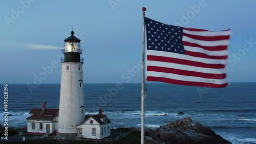 A white lighthouse tower stands as a beacon of safety on the Maine coastline, its red accents a landmark against the vast ocean and sky
