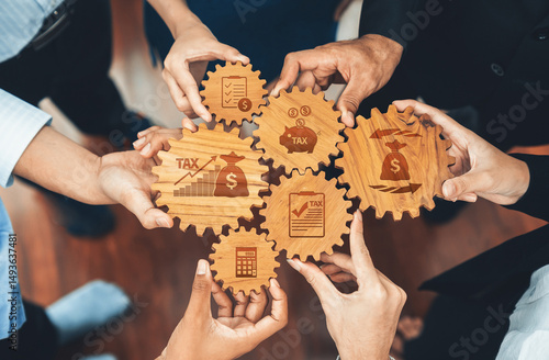 A diverse group of hands holding wooden gears featuring tax symbols and financial elements. This image symbolizes teamwork in financial planning and tax strategy development. Amity