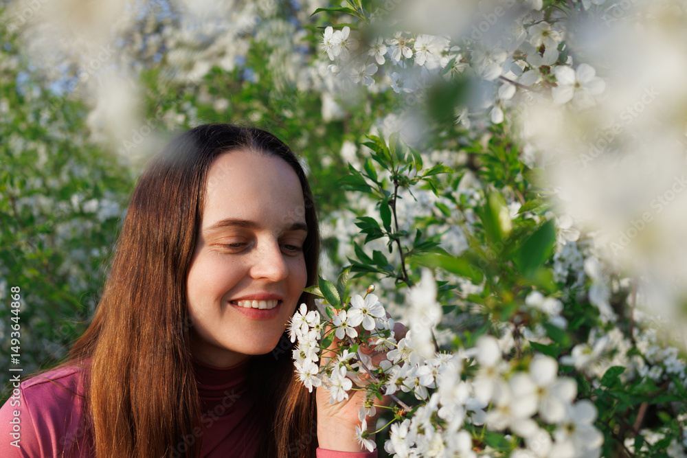 Fototapeta premium Woman with eyes closed serenely smells white flowers outdoors, enjoying nature's scent, peaceful moment, free from allergies.