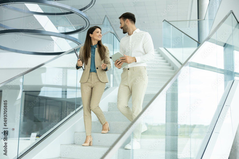 A woman and man walk together in a stylish office, discussing ideas and enjoying a productive atmosphere. A woman and man walk together in a stylish office, discussing ideas and enjoying a productive atmosphere.