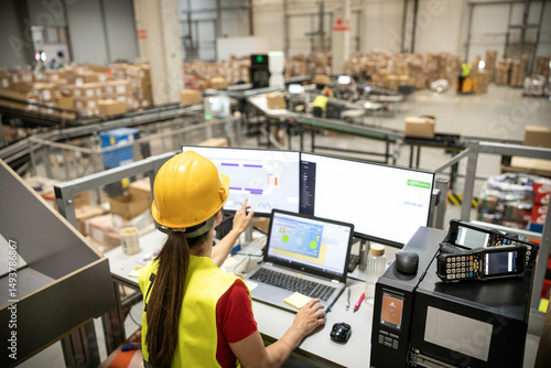 A woman is analyzing real-time data on her computer within a warehouse, demonstrating tech integration in logistics.