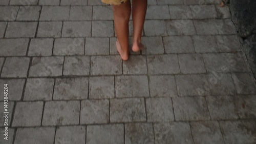 A person is walking barefoot on a brick sidewalk