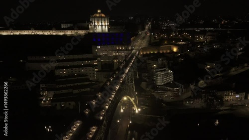 Drone orbits to the right over Luis I Bridge at night facing the Gaia side in Porto, Portugal