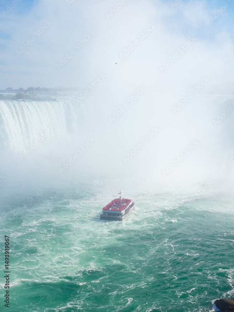 Obraz premium Niagara Falls. A pleasure boat with people near the huge famous waterfall. View from the Canadian side. Nature scenery. Photo for advertising, background, wallpaper, postcards.