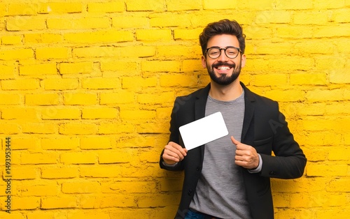 Smiling Man Holding Blank Card Yellow Brick Wall Background