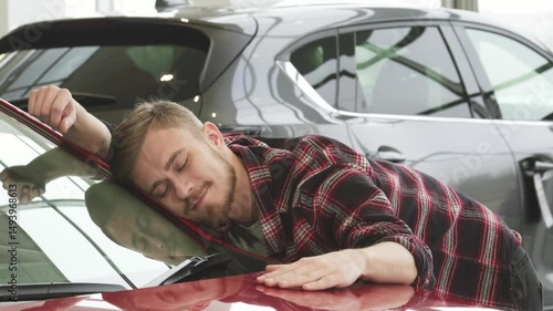 Joyful man embracing his new car with a thumbs up at the dealership