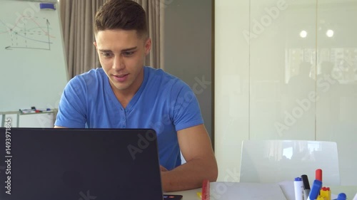 Focused young man working on laptop in modern office