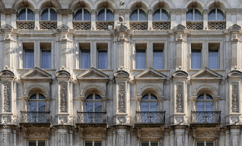 Fototapeta premium A stunning European style of Wrought iron black railings balconies and Classic glass windows in residential tenement building with London victorian architecture. use it as your Wallpaper, Poster.