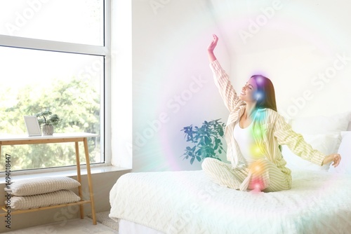 Morning of beautiful young woman with colorful aura sitting on bed