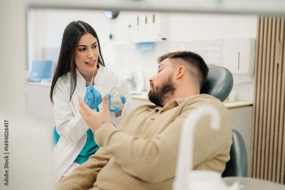 Obraz premium Dentist showing teeth model to patient in dental clinic