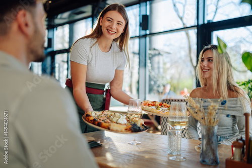 Waitress serving pizza to customers in restaurant