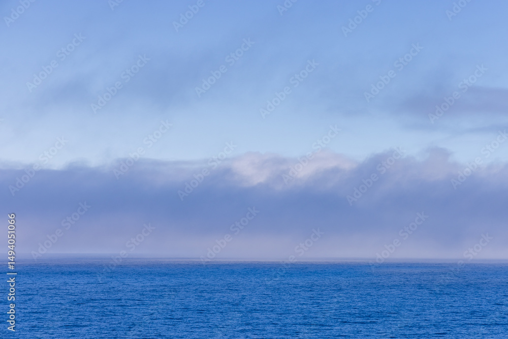 Obraz premium Serene Ocean Horizon with Soft Clouds in the Distance Over Pacific Ocean
