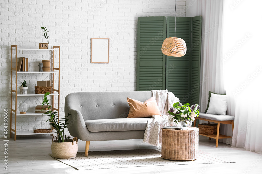 Obraz premium Sofa and wicker coffee table with blooming lilac branches in interior of living room