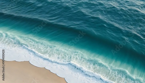 Aerial view showing the turquoise ocean waves meeting the light tan sandy beach on a sunny day.