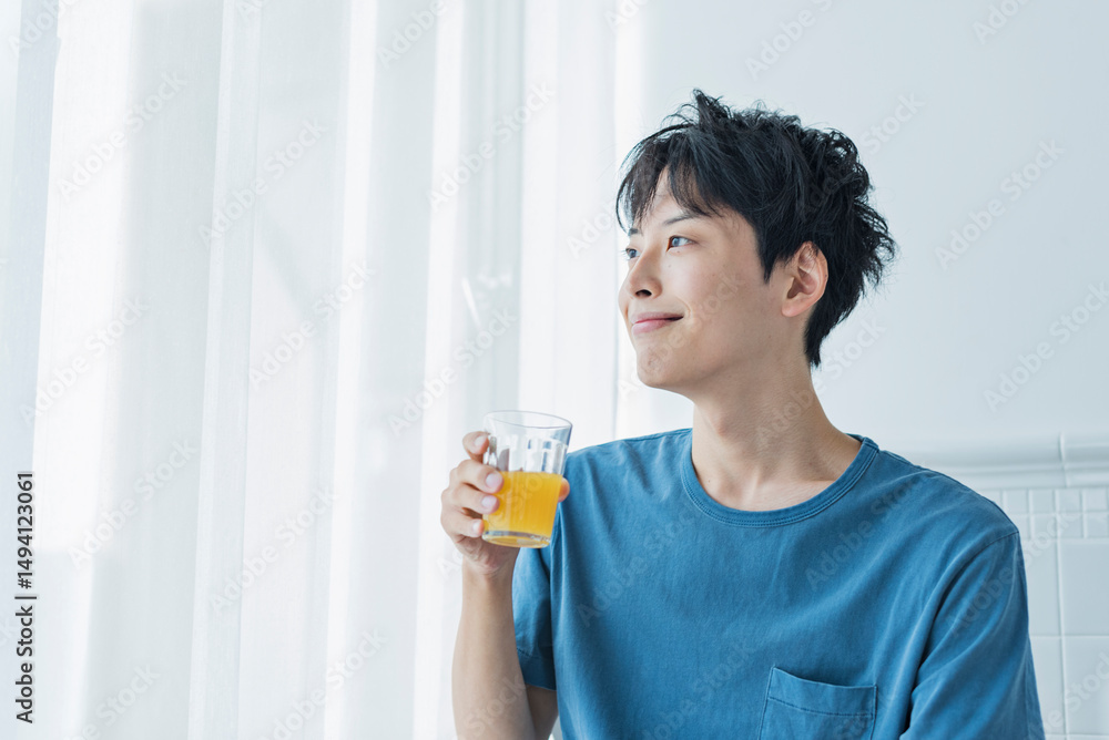 朝にオレンジジュースを飲む若い男性 朝にオレンジジュースを飲む若い男性