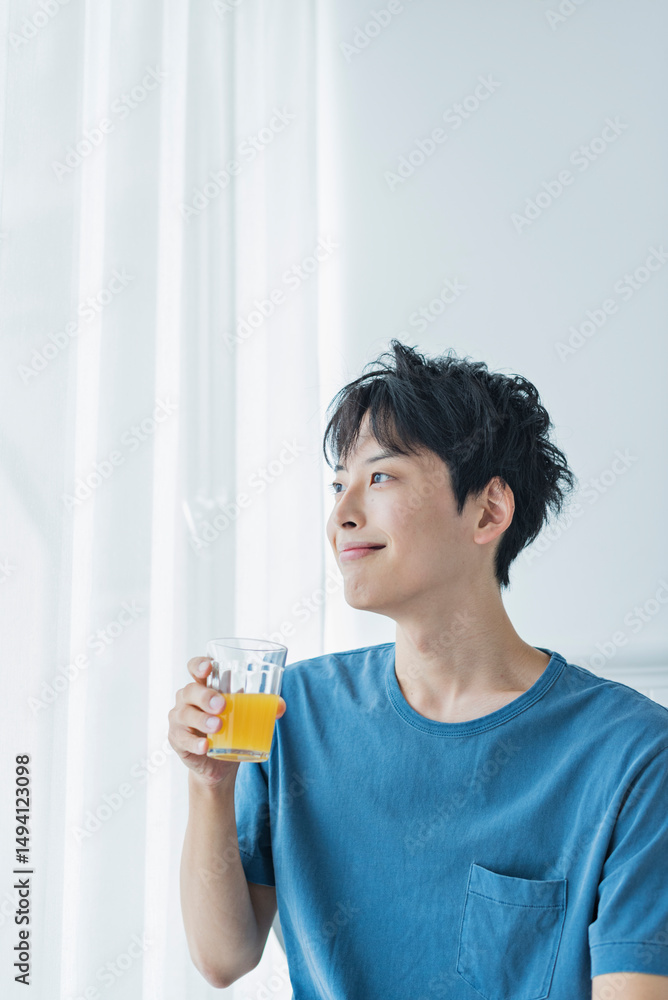 朝にオレンジジュースを飲む若い男性 朝にオレンジジュースを飲む若い男性