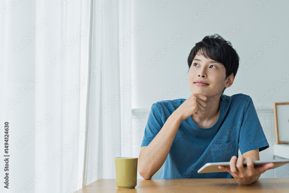 Naklejka premium 休日にタブレット端末で動画を見る若い男性