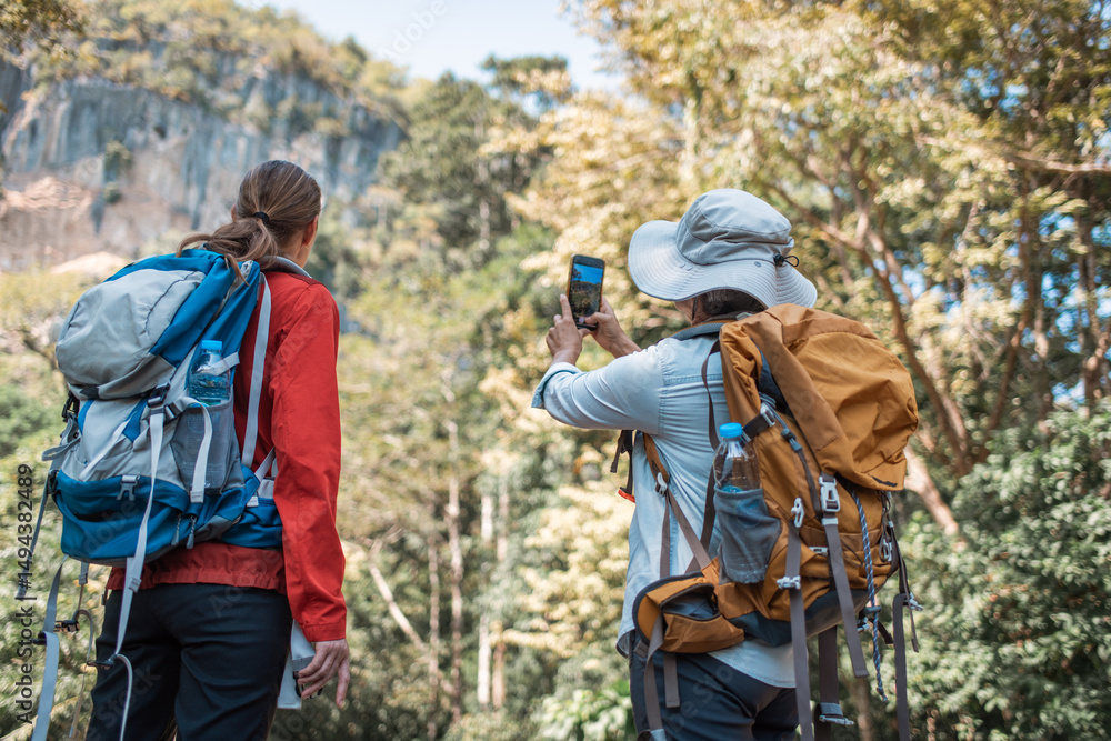 Hikers or explorers family on journey carrying backpack, trekking poles looks into the distance observing guide trekking and trail exploration holiday ecotourism concept Hikers or explorers family on journey carrying backpack, trekking poles looks into the distance observing guide trekking and trail exploration holiday ecotourism concept