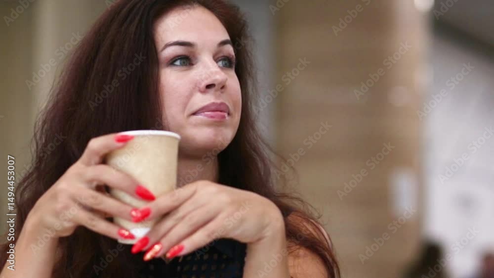 Close-up portrait of a beautiful woman with dark hair holding a paper cup for hot drinks, manicure, nails painted red. Close-up portrait of a beautiful woman with dark hair holding a paper cup for hot drinks, manicure, nails painted red.