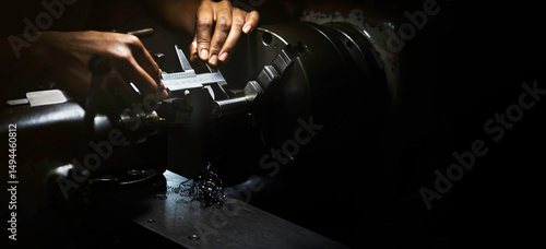 Tableau sur toile Lathe operator using a vernier caliper to measure steel workpiece dimensions at
