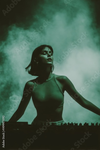 Female DJ with raised hand, heavy stage fog and warm rim lighting, in background smoke and lasers flooding scene. Live DJ show.