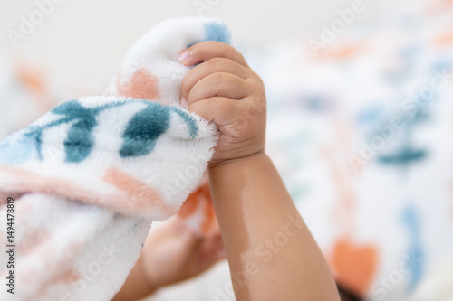 One year old asian girl joyfully holding blanket at home cozy environment playful moment