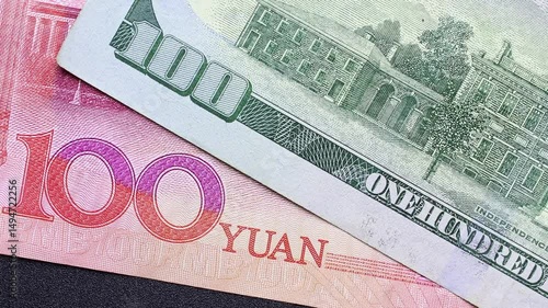 Close up view of rotating Chinese Yuan (CNY) and American Dollar (USD) banknotes. Concept of  international trade restrictions, tariff wars for economic dominance, USA and China reciprocal sanctions.