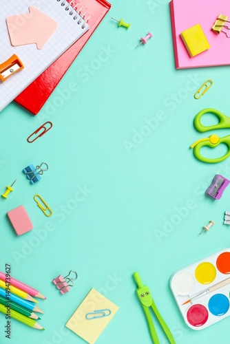 A vertical collection of brightly colored school supplies including notebook, stationery, displayed on a color background